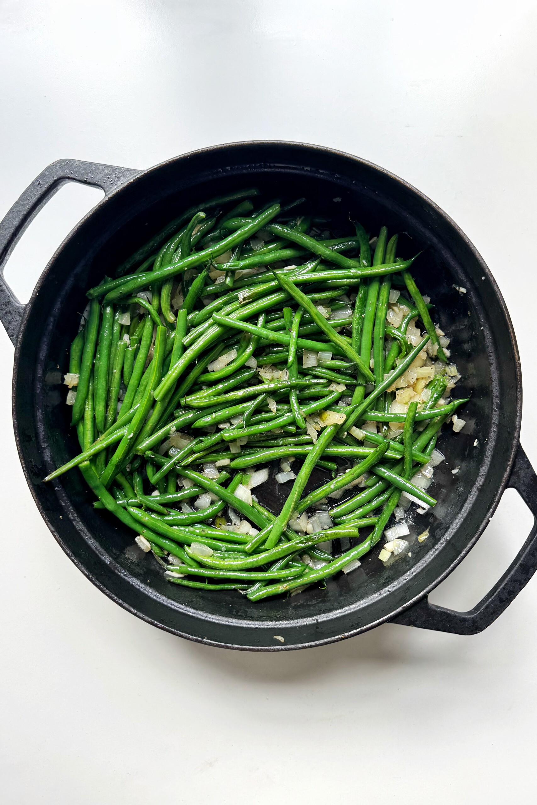green beans and garlic and onions in black dish.