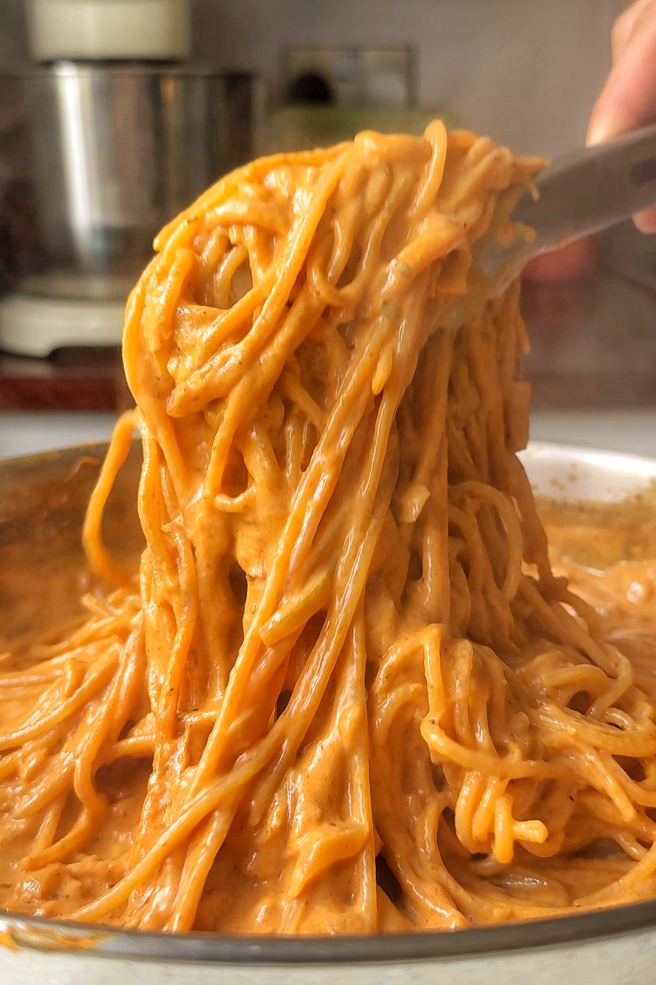 Scooping up spaghetti with tongs.