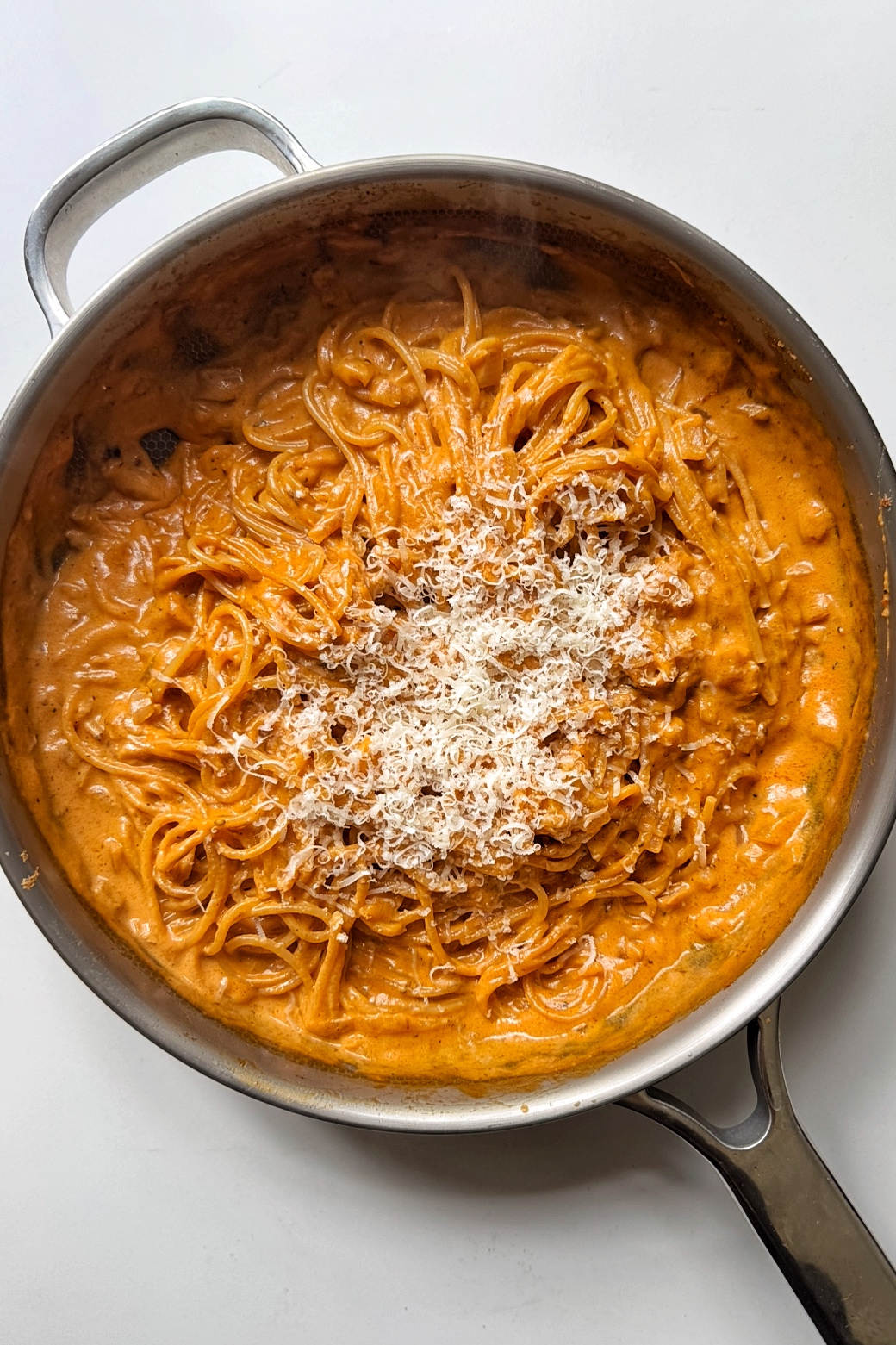 Grated parmesan on sun-dried tomato pasta.