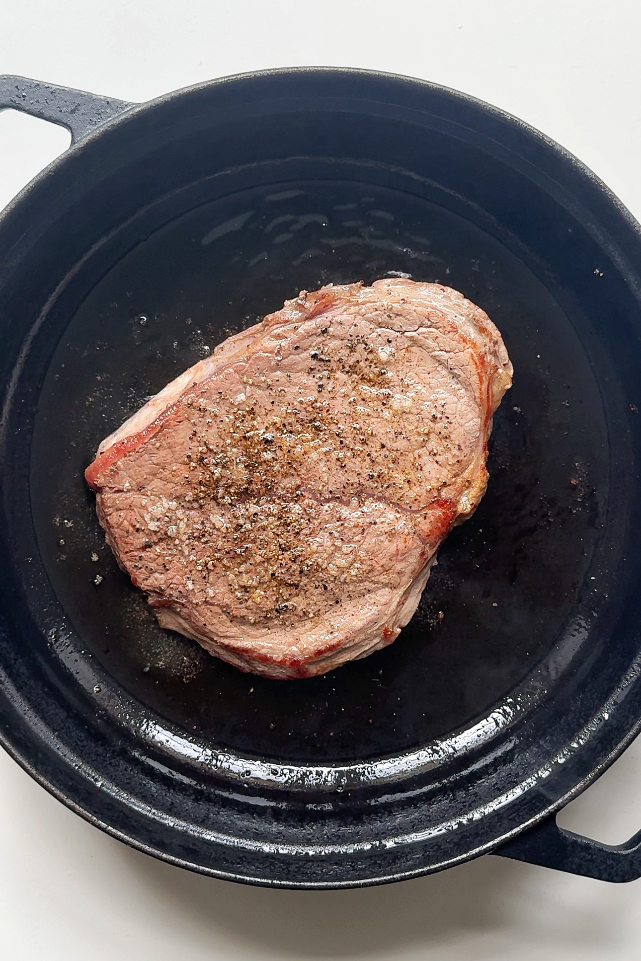 Frying beef in black pan.