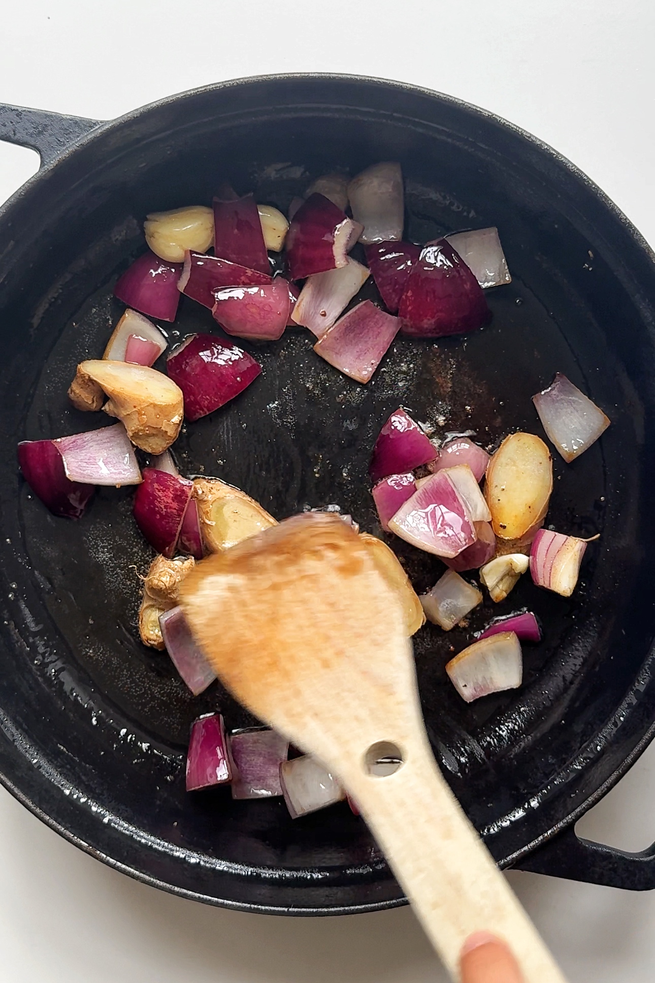 Frying garlic, ginger, and onion in a pan.