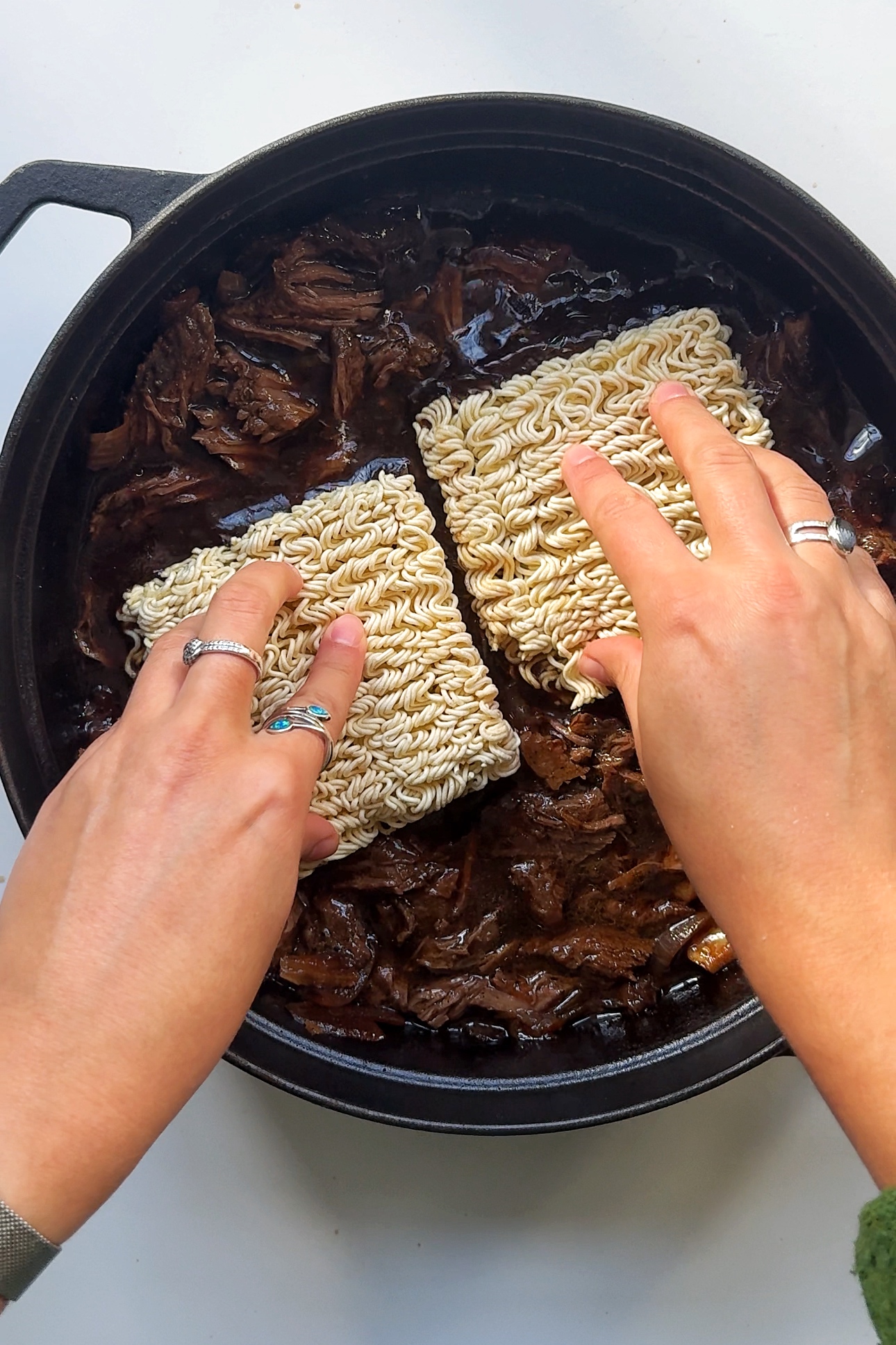 Adding ramen noodles in beef pan.