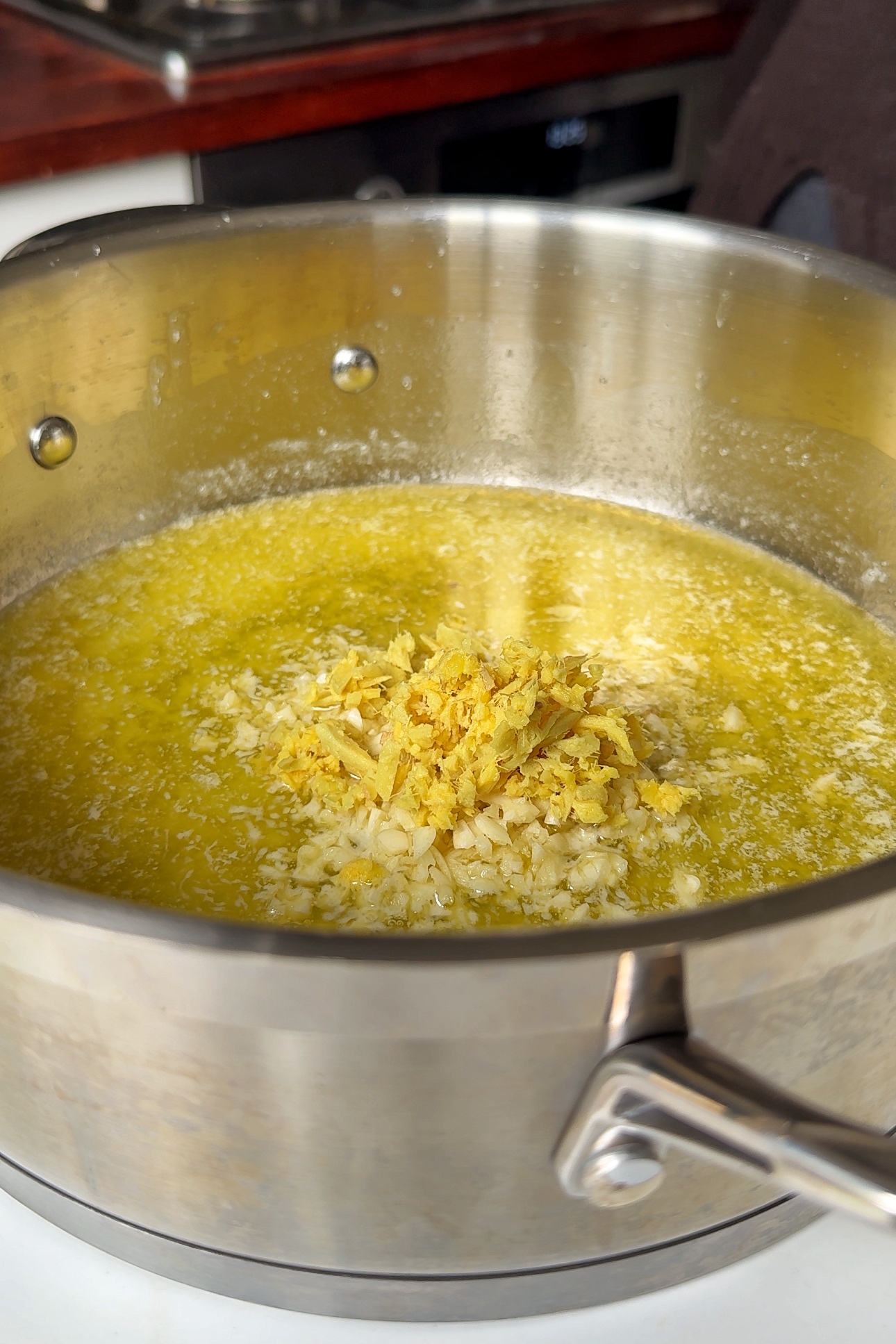 Adding garlic and ginger into buttered pan.
