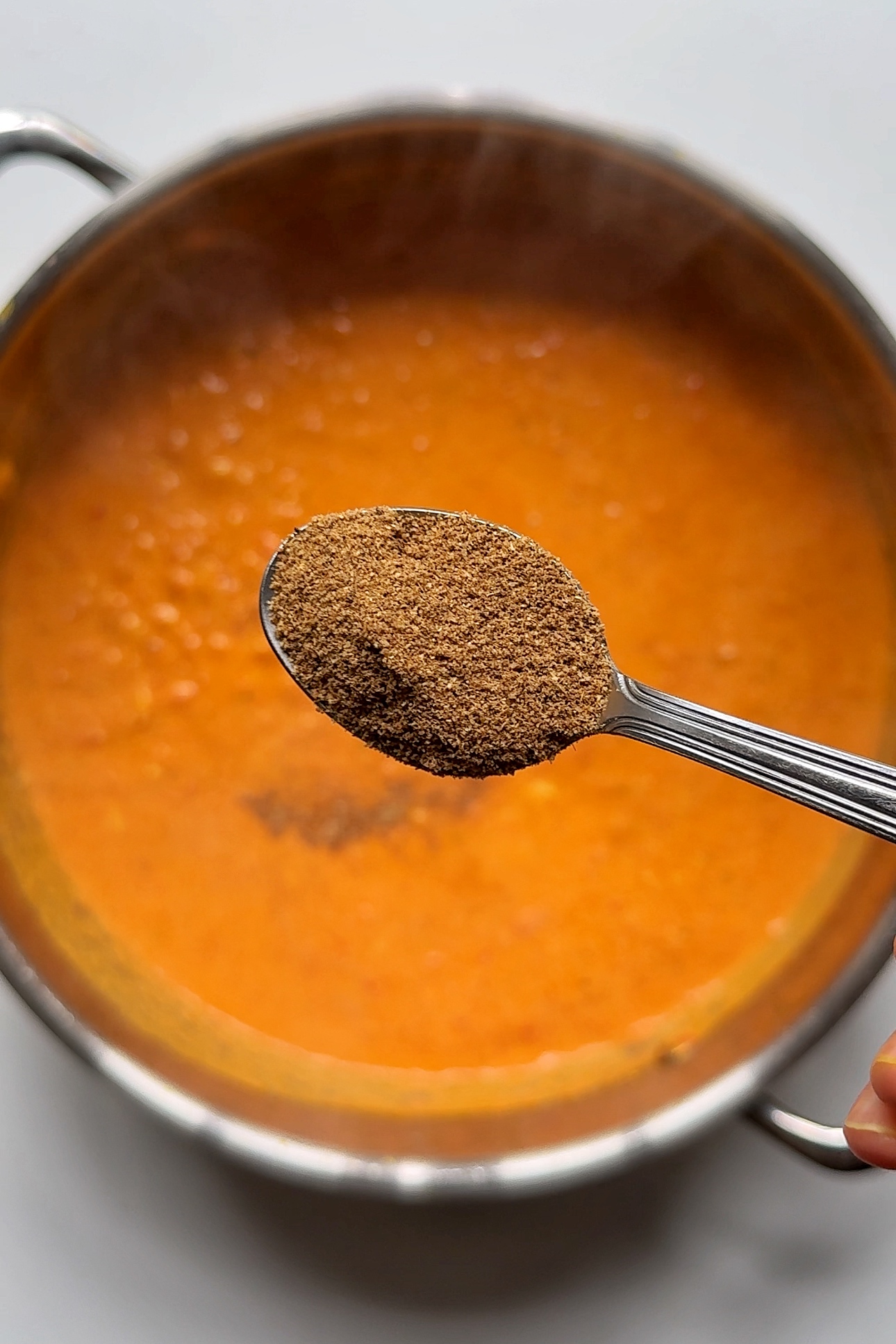 Adding garam masala to egg curry sauce.