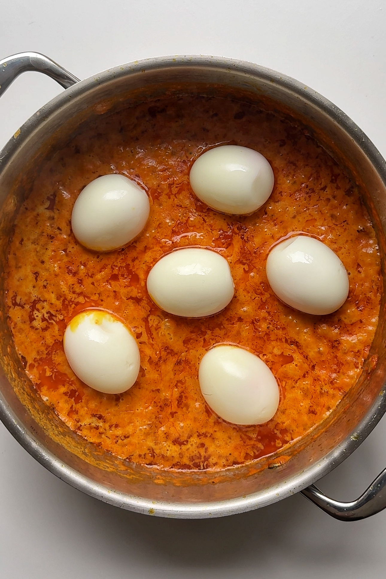 Adding eggs to egg curry sauce.