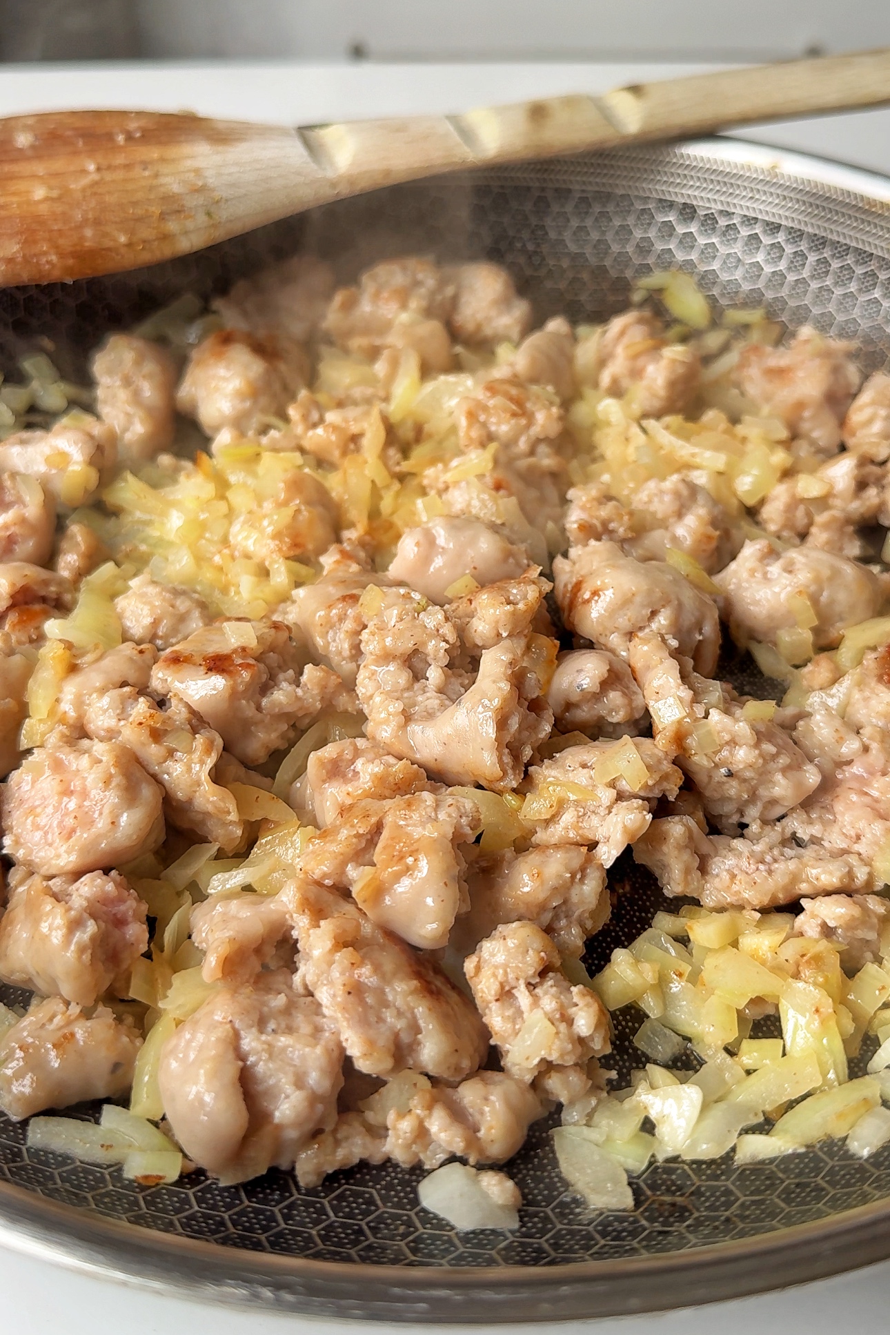 Frying sausages with onion and garlic in a pan.