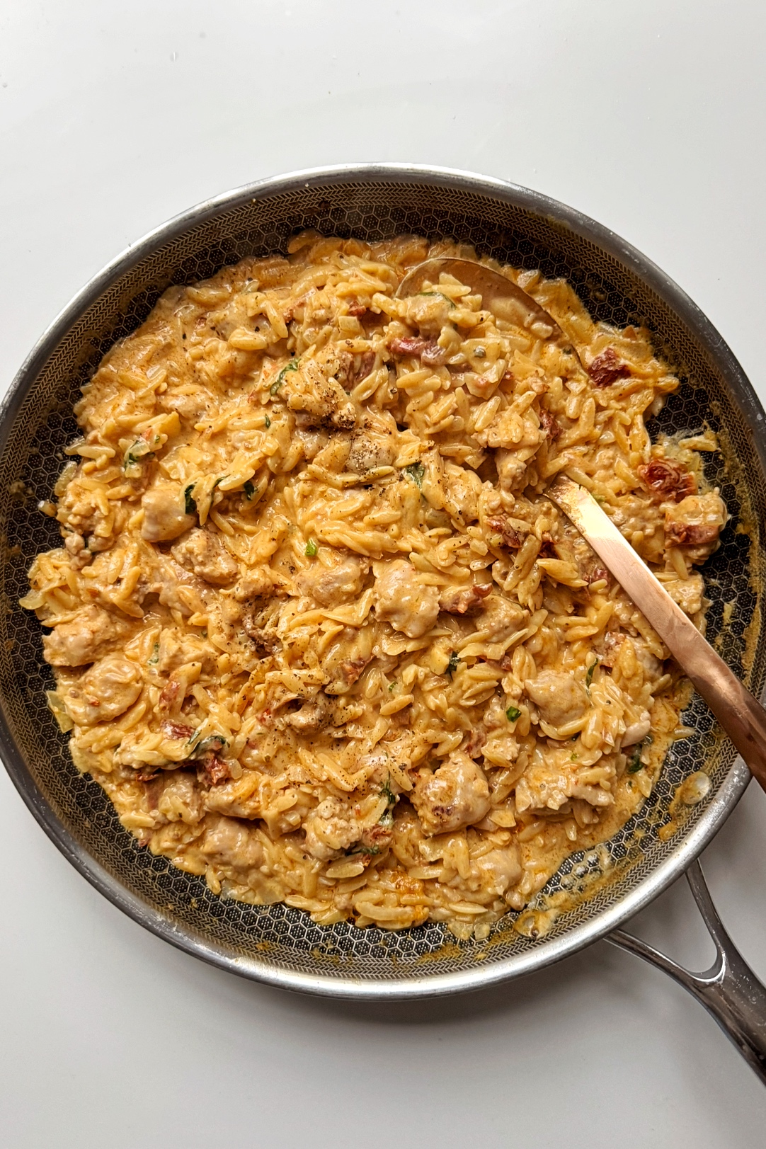 sausage orzotto in a black pan.