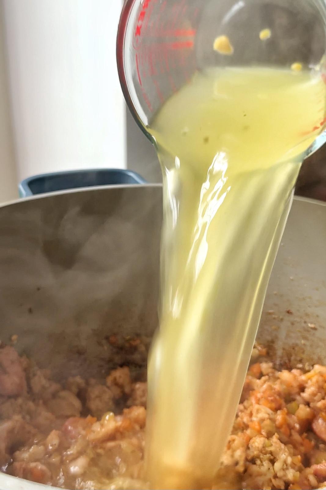 Adding chicken stock into Christmas lasagna ragu.