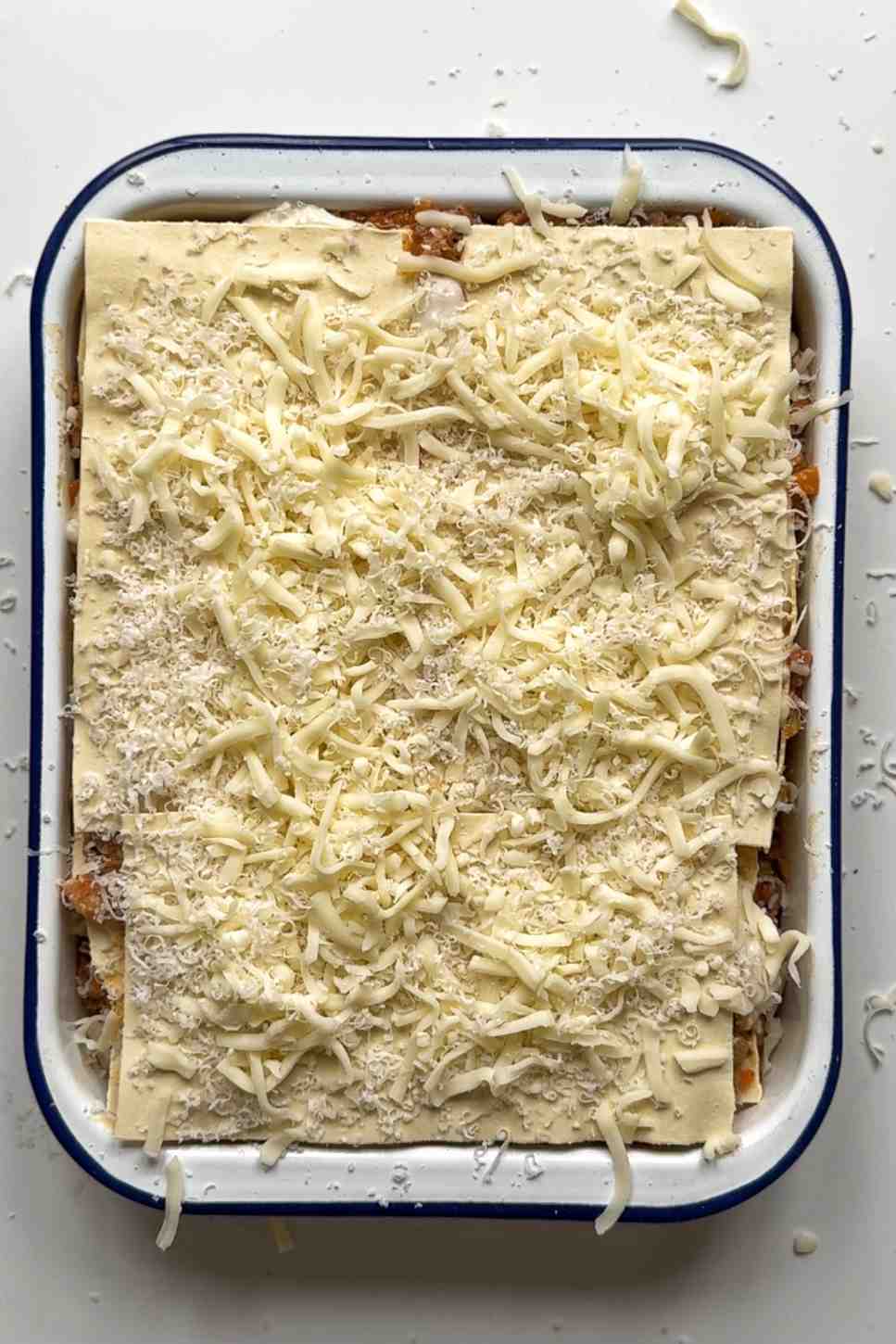 Topping Christmas lasagna with parmesan and mozzarella cheese.