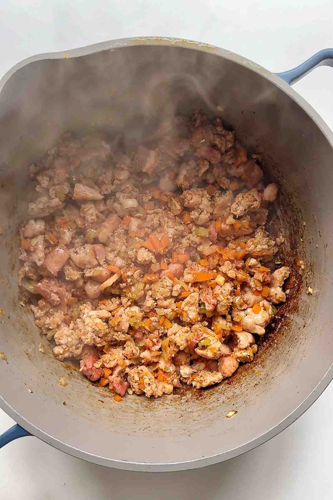 cooking sausage and lardons in pot for Christmas lasagna.