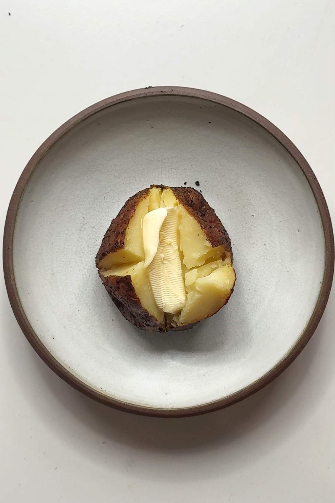 Adding butter to baked potato.