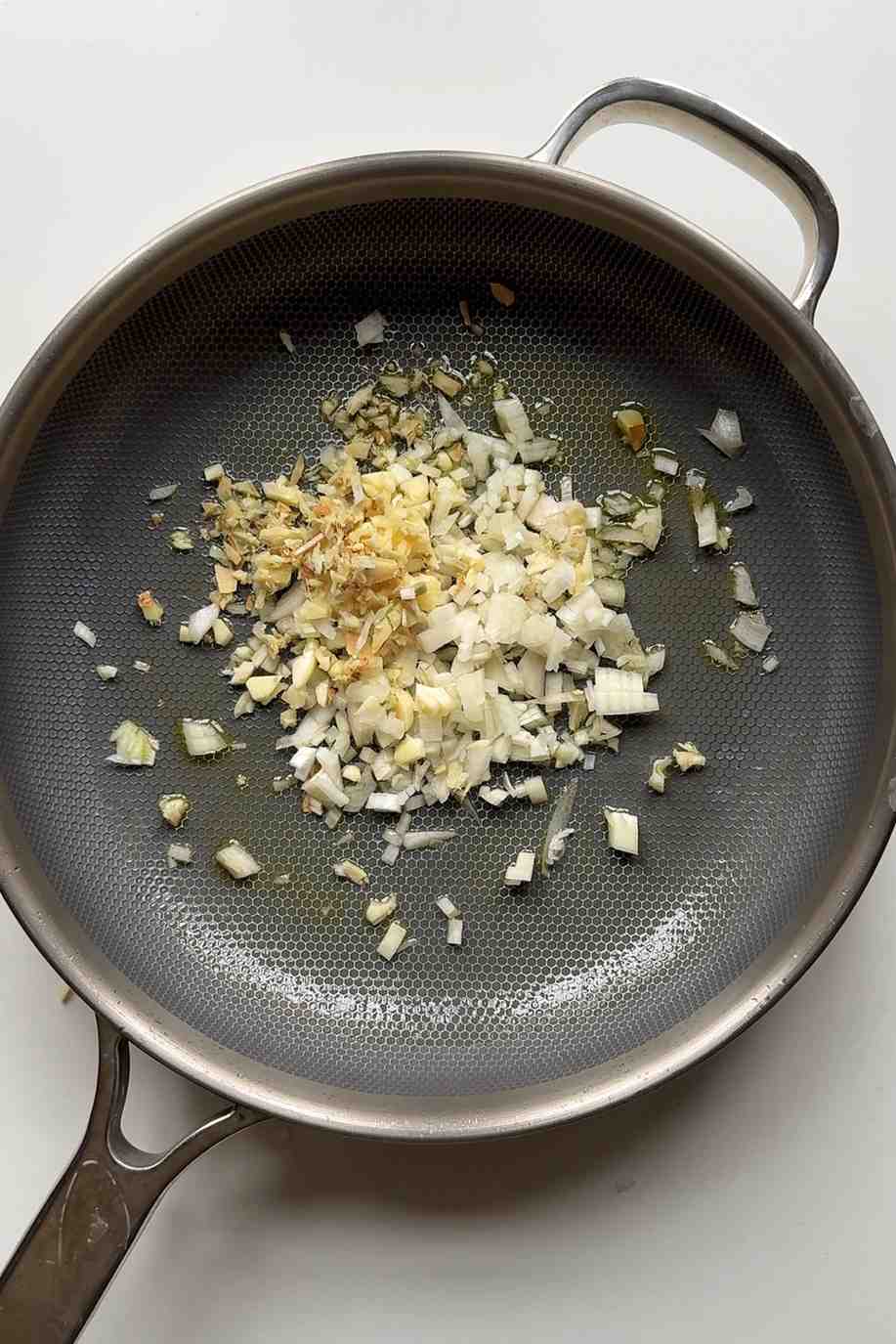 Frying garlic, onion, and ginger in a pan.