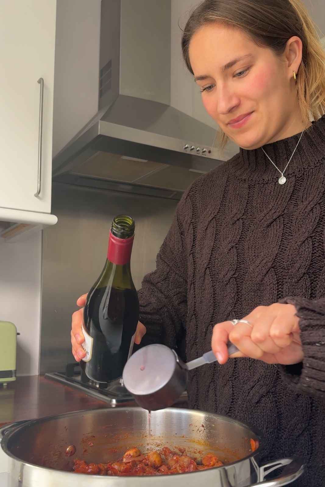 Emily Roz pouring red wine into the mushroom bourguignon pot.