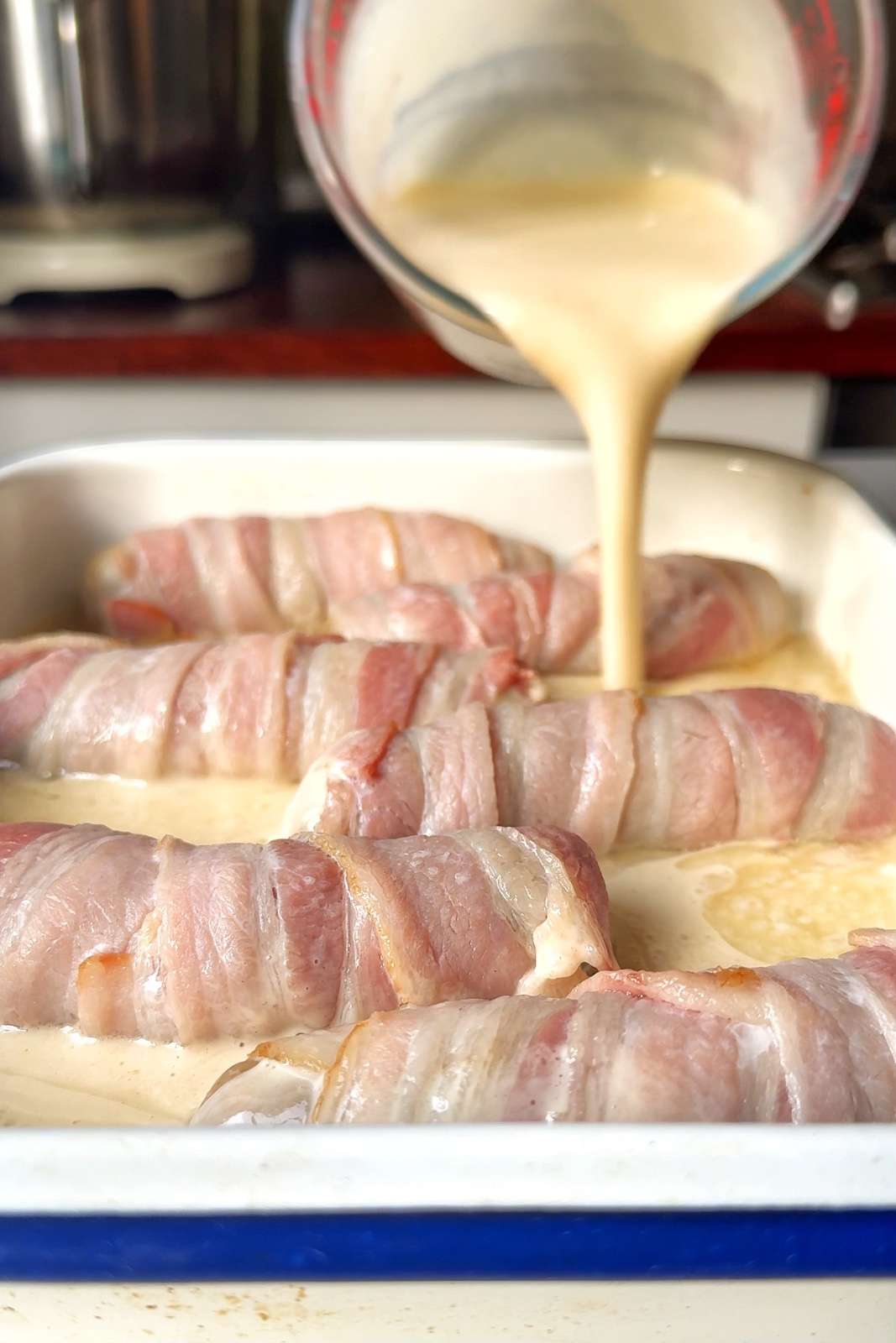 Pouring batter into pigs in blankets tray.