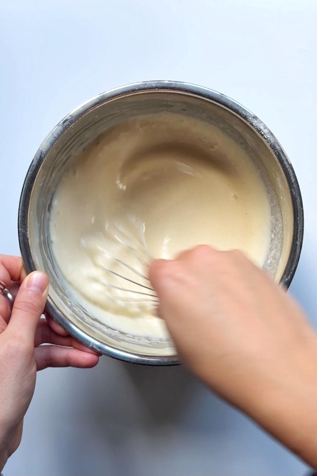 Whisking the pigs in blankets toad in the hole batter.