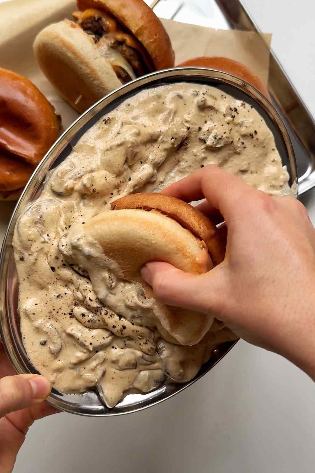 dipping the burger into the sauce.