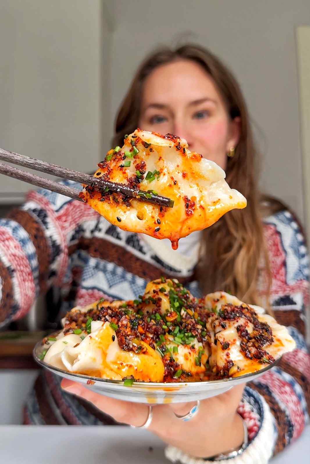 Emily Roz holding up a dumpling to the camera.