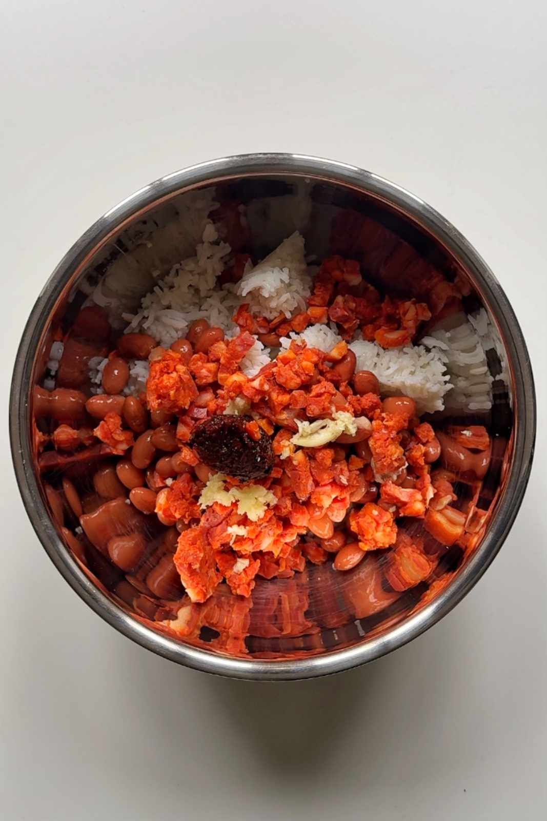 Mixing rice and beans in a metal bowl.