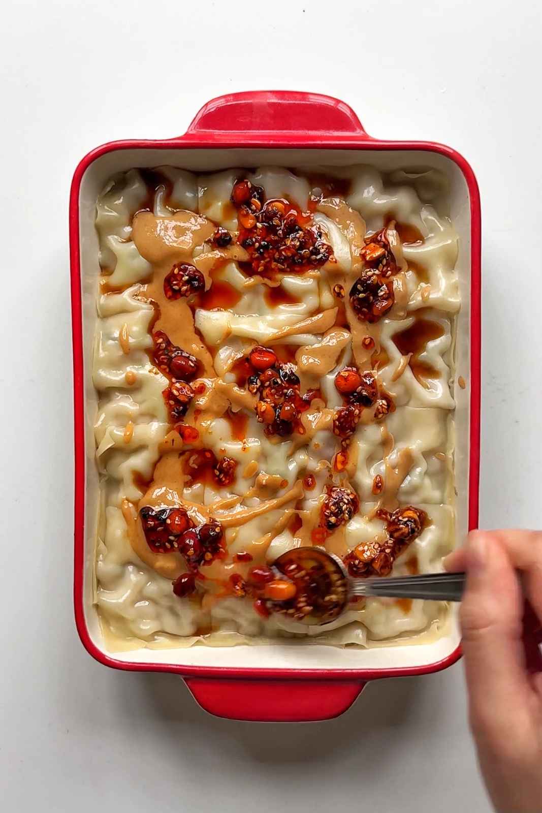 Topping the viral dumpling lasagna with chilli oil.