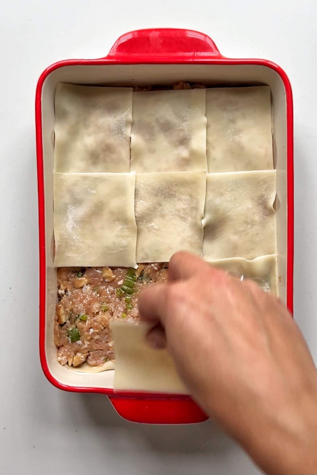 Layering the dumpling lasagna.
