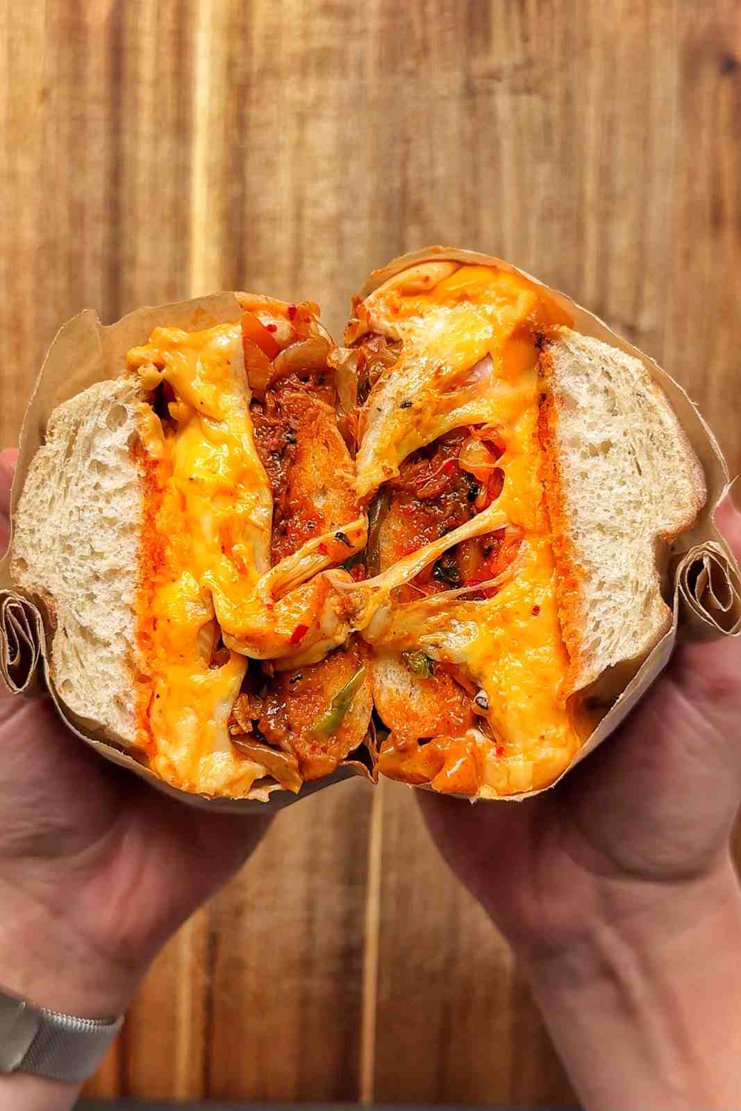 Wrapping bulgogi cheesesteak sandwich in parchment paper and showing the cross section.