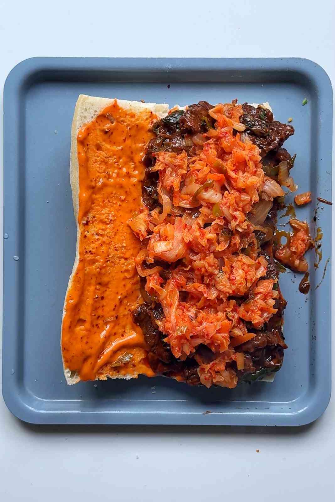 Assembling the bulgogi cheesesteak sandwich.