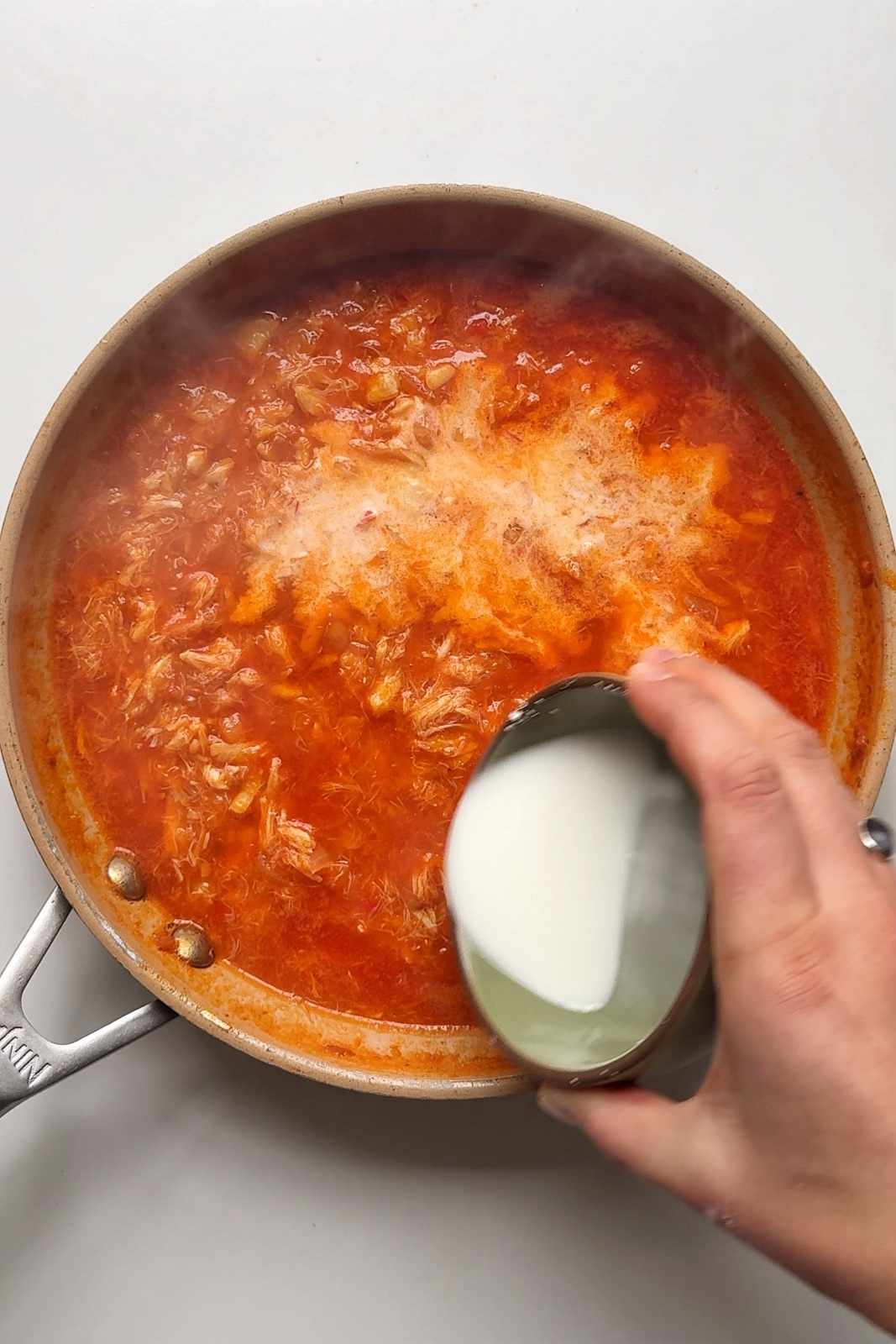 Pouring cornstarch into chilli crab sauce.