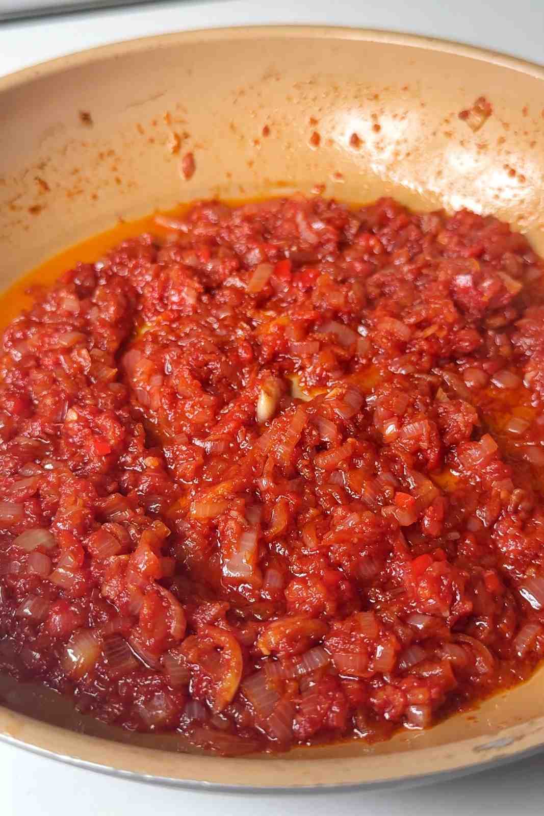 Frying tomato paste in ginger and garlic mixture.