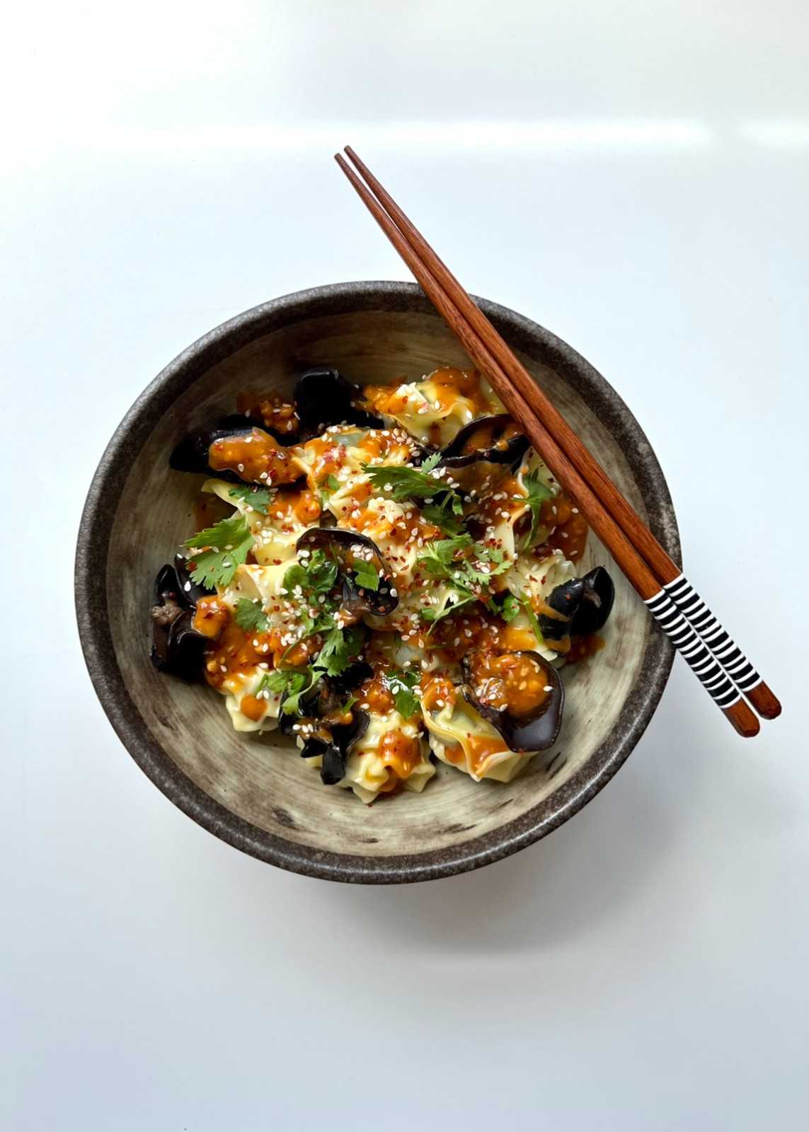 A top-down view of a bowl of Wood Ear Mushroom Wontons in a Peanut Chilli Oil Sauce.