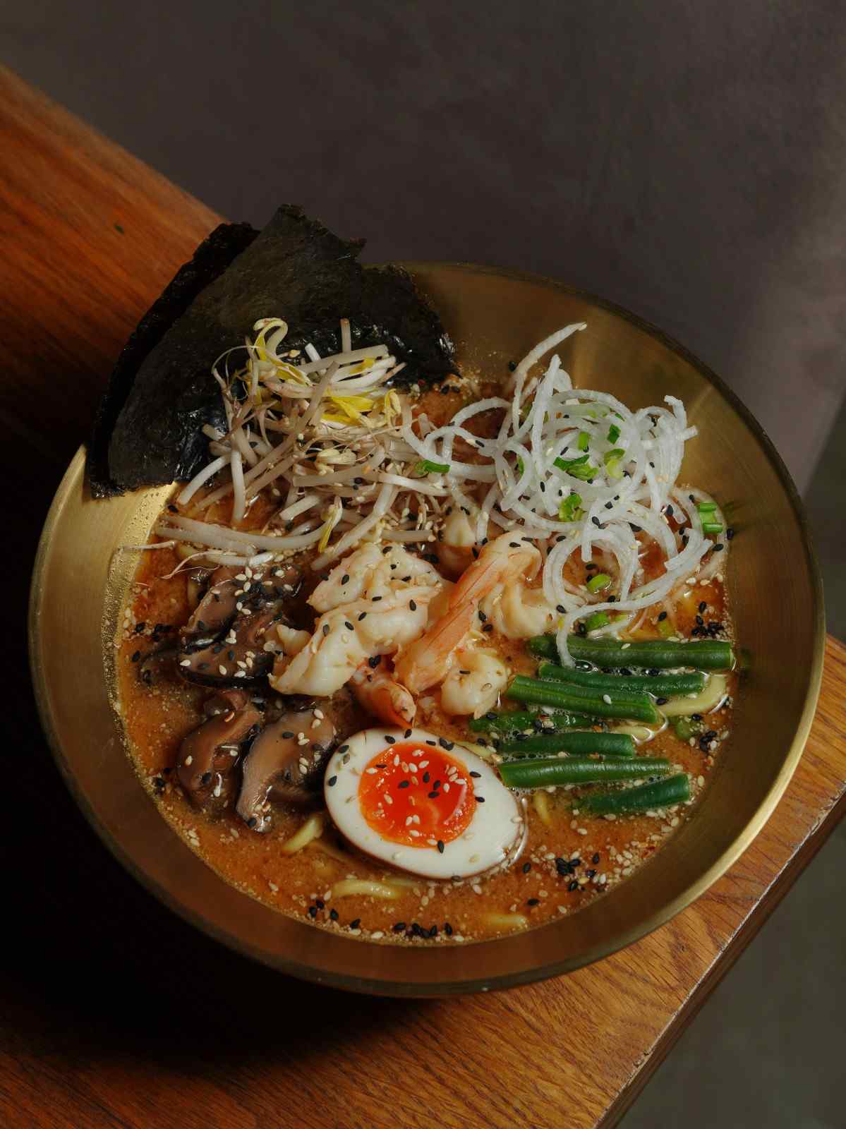Crisp rectangular sheets of Nori (dried seaweed) tucked vertically into the edge of a steaming bowl of ramen using the "Nori Shield" technique to prevent sogginess while adding an umami-rich aroma.