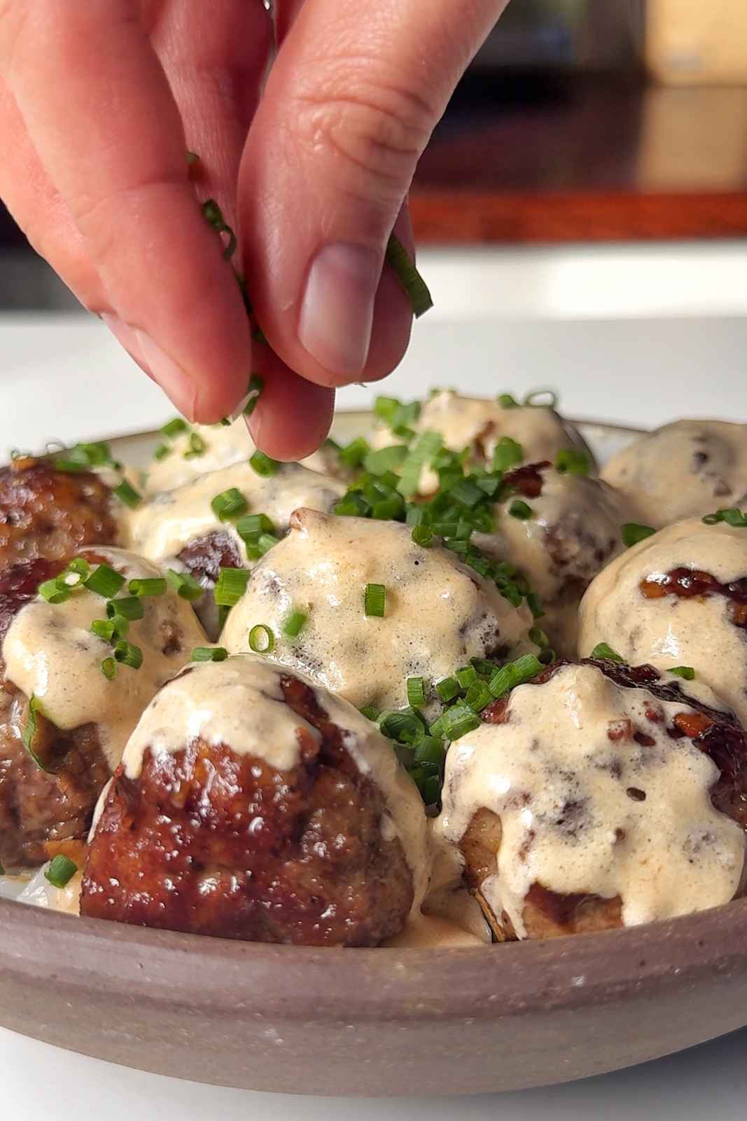 Adding chives onto the teriyaki meatballs.